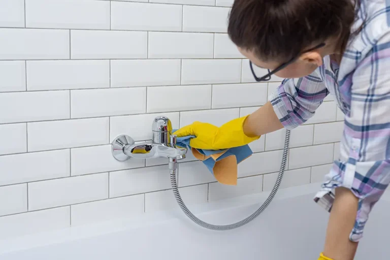 Professional cleaner removing water stains from a faucet
